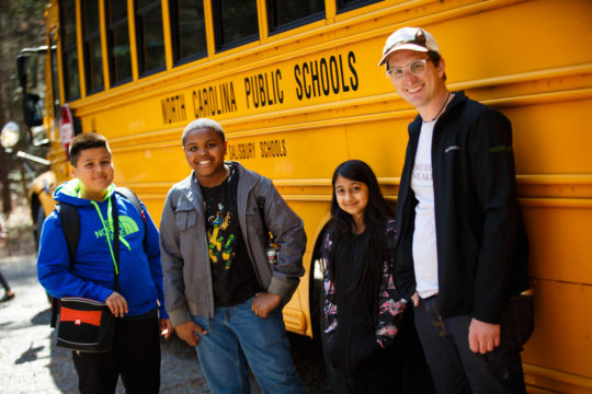 Muddy Sneakers instructor and students stand in front of a North Carolina Public Schools school bus