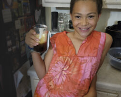 Muddy Sneakers student, Eden, poses with a glass of her homemade sassafras root beer.