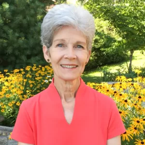 Missing Rankin stands in front of a garden filled with black-eyed susan flowers, smiling at the camera.