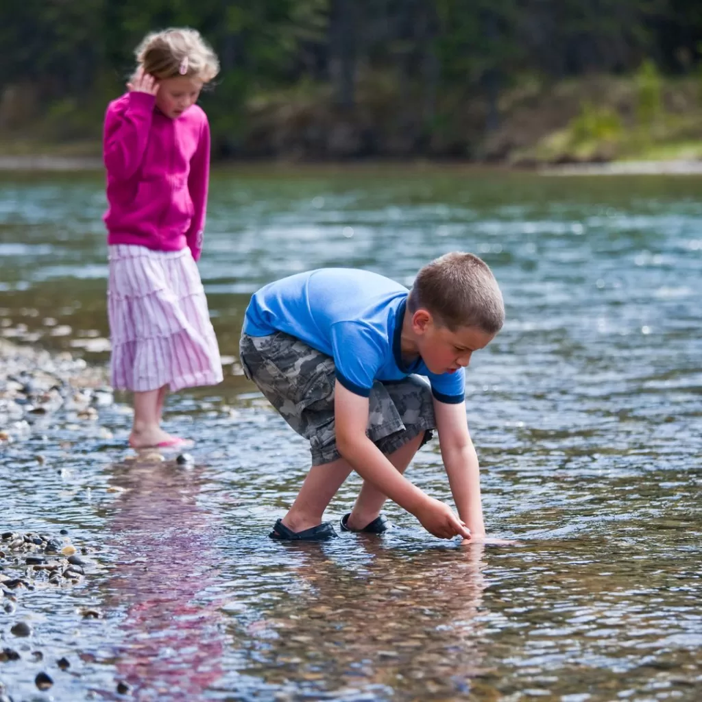 Siblings playing in shallow area of creek.