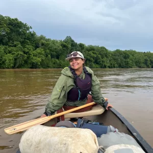 Natalie Marbury smiling at the camera from her seat across a canoe.