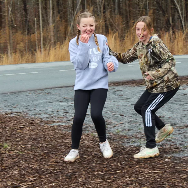 A student laughs as another student tags them during an active outdoor game
