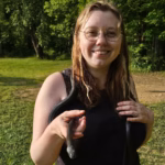 Eden Simmons smiling at the camera, posing with a black snake.