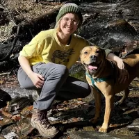 Muddy Sneakers Field Instructor Emma Hanna and her dog smile at the camera.