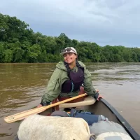 Natalie Marbury smiling at the camera from her seat across a canoe.